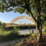 River landscape with arched bridge framed by trees – fine art landscape photography by Layne Morgan