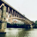 Steel bridge spanning a river under soft daylight – fine art urban landscape photography by Layne Morgan