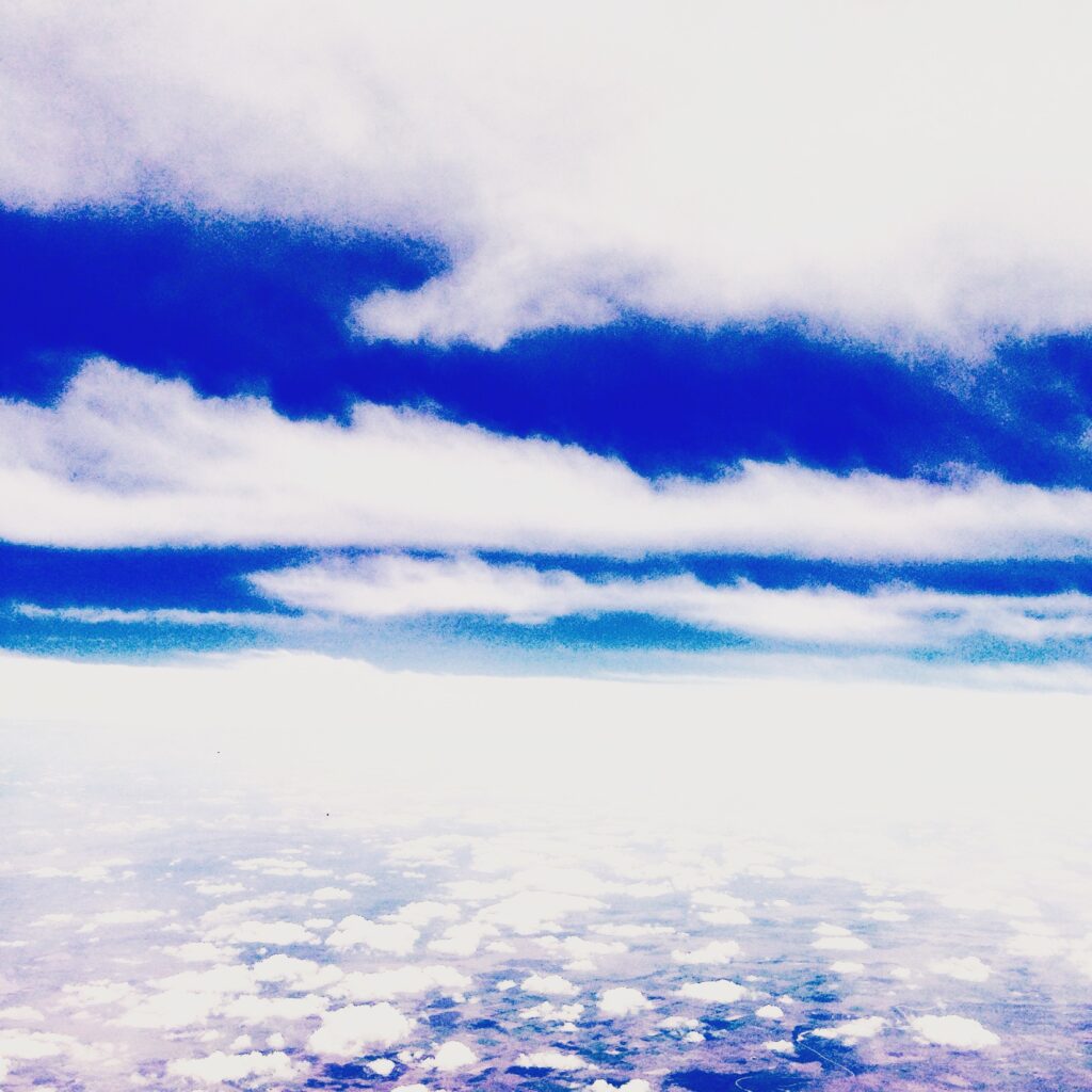 Dramatic blue sky and white cloud formations photographed from above, fine art cloud photography by Layne Morgan.