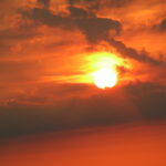 Fine art photograph of glowing sunset clouds with the sun breaking through the sky