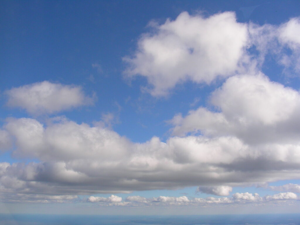 Large white cumulus clouds in blue sky – fine art cloudscape photography by Layne Morgan