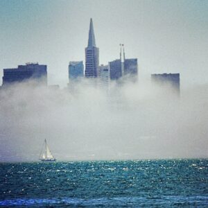 Fog-covered city skyline emerging above ocean horizon fine art landscape photography by Layne Morgan
