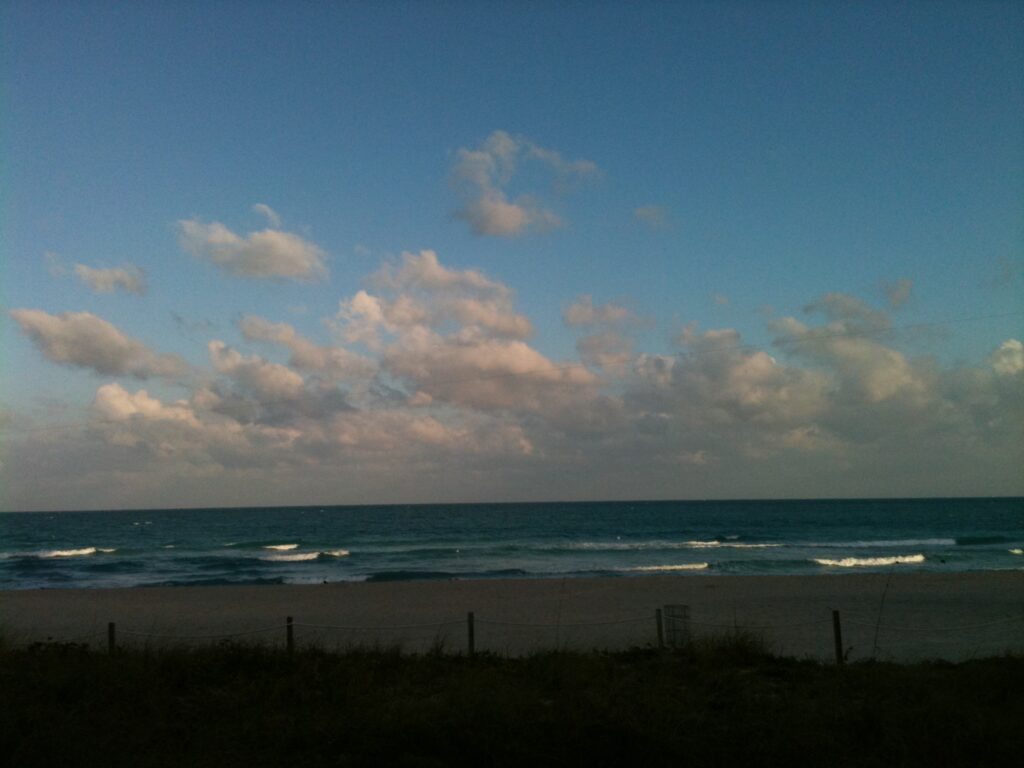 Blue sky with scattered clouds above a calm ocean horizon coastal landscape
