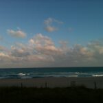 Blue sky with scattered clouds above a calm ocean horizon coastal landscape