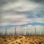 Desert landscape with wind turbines under dramatic sky photography by Layne Morgan