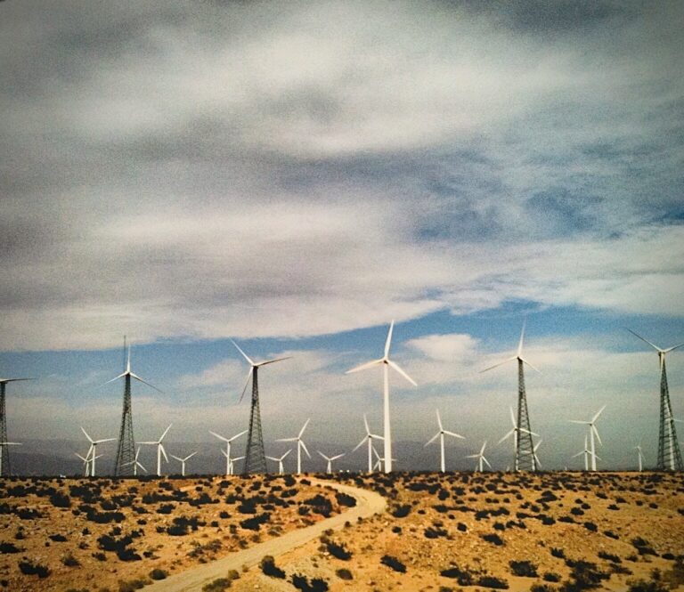 Desert landscape with wind turbines under dramatic sky photography by Layne Morgan