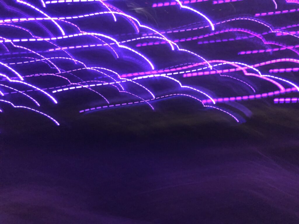 Purple long-exposure light trails forming abstract wave patterns – experimental photography by Layne Morgan