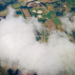 Aerial view of clouds drifting above land and landscape below