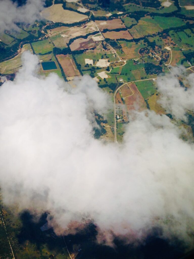 Aerial view of clouds drifting above land and landscape below
