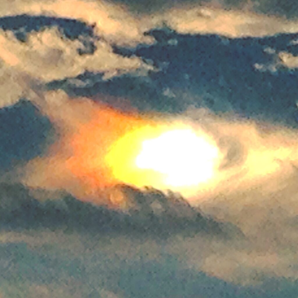 Sun breaking through dramatic clouds above the ocean in a coastal seascape