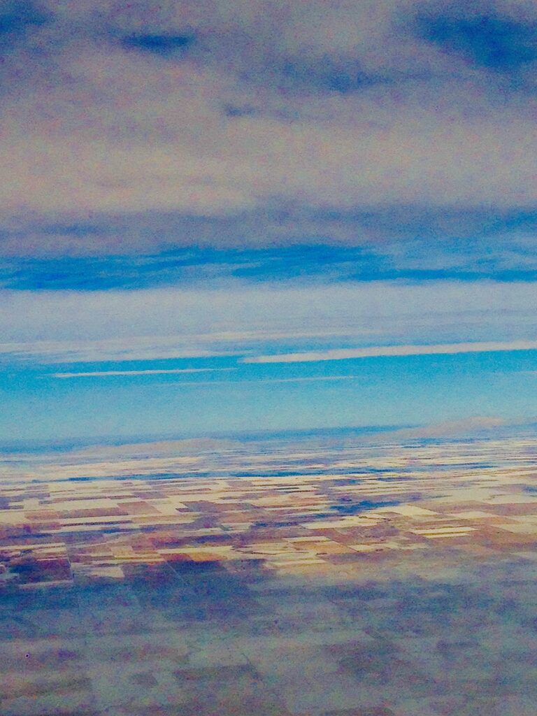 Pastel coastal seascape with colorful reflections across the ocean horizon