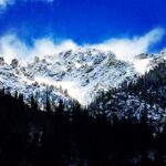 Snow covered mountain range under dramatic blue sky landscape photography by Layne Morgan