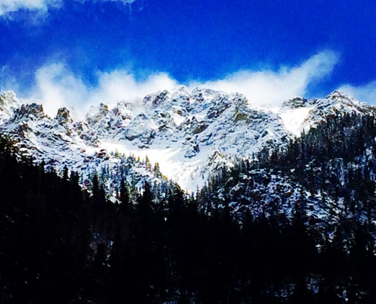 Snow covered mountain range under dramatic blue sky landscape photography by Layne Morgan