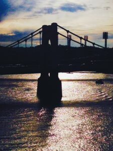 Suspension bridge silhouette over water at sunset fine art architectural photography by Layne Morgan