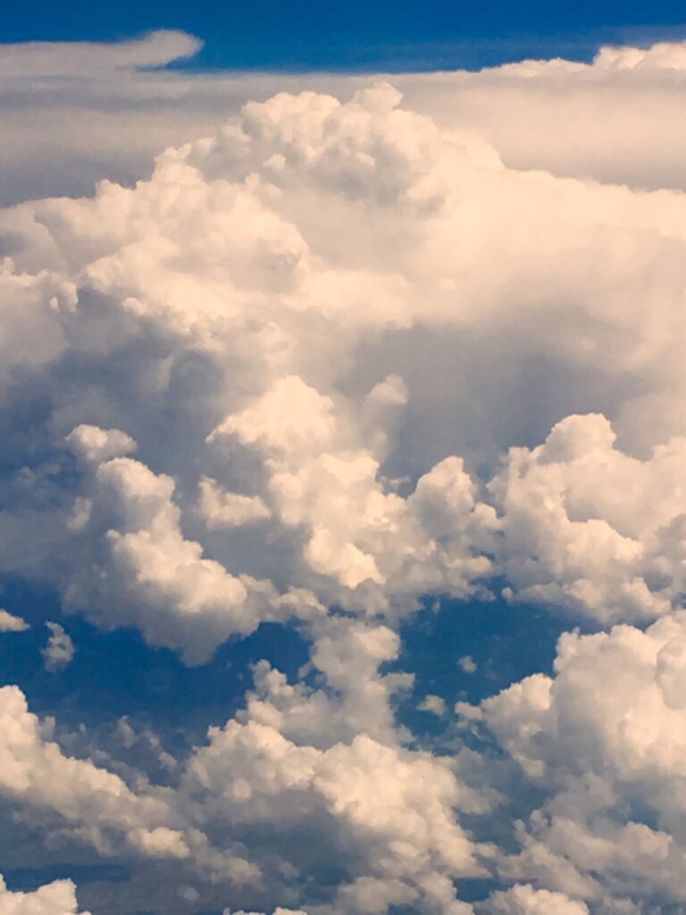 Golden sunlight illuminating cumulus clouds in blue sky – fine art cloudscape photography by Layne Morgan