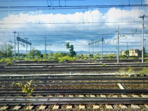 Railway tracks stretching across industrial train yard under blue sky urban infrastructure photography by Layne Morgan