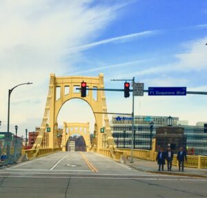 City roadway leading toward monumental arch bridge structure urban architecture photography by Layne Morgan