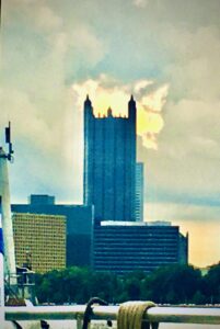 Modern blue skyscraper skyline rising above city buildings architectural photography by Layne Morgan