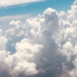 Towering white clouds rising above the landscape from an aerial perspective