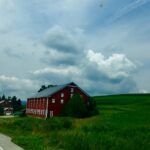 Red barn in green countryside field under dramatic sky fine art photography by Layne Morgan