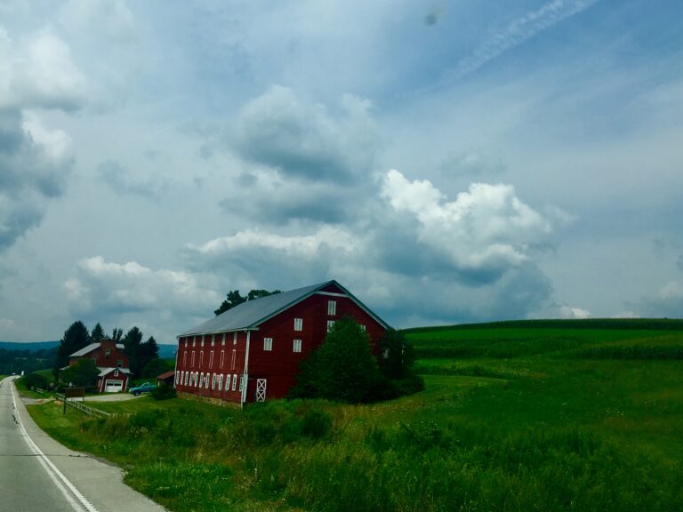 Red barn in green countryside field under dramatic sky fine art photography by Layne Morgan