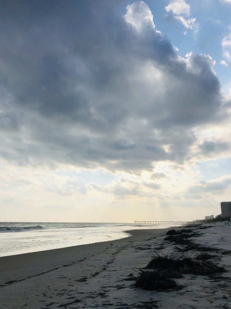 Storm clouds gathering above a coastal shoreline with ocean waves