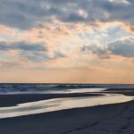 Sunset clouds glowing above a quiet beach shoreline and ocean horizon