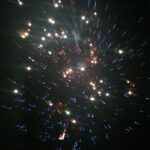 Abstract photograph of sparkling light particles forming a starburst effect against a dark background, creating a dynamic fine art composition