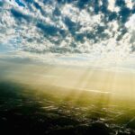 Sun rays breaking through clouds in a bright sky, fine art landscape photography by Layne Morgan